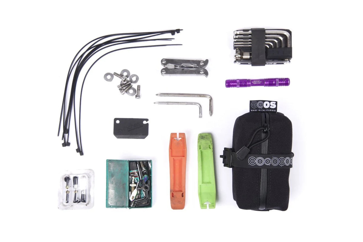 Outer Shell Mini Saddlebag, laid out with spare parts and tools it holds