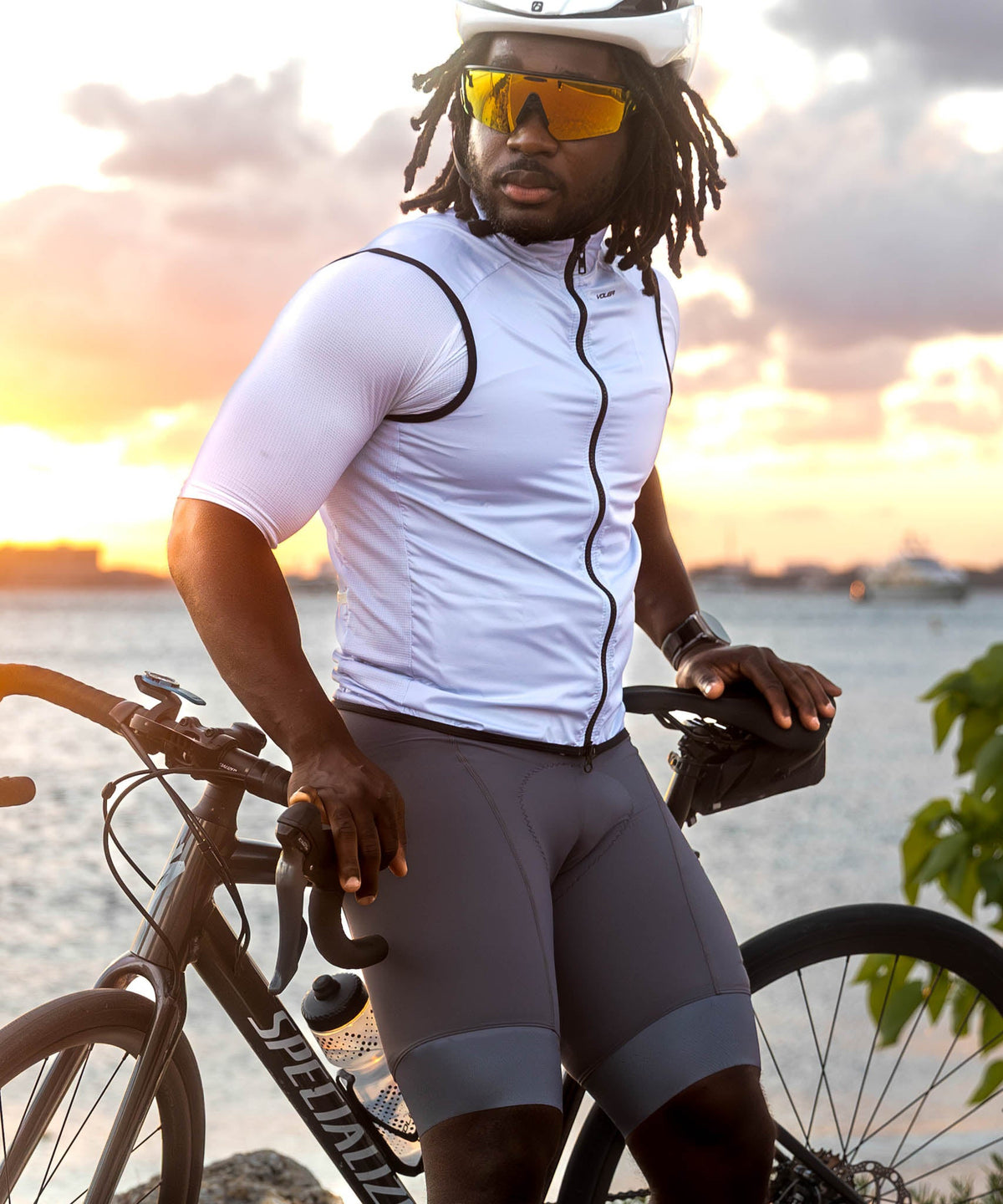 Voler Men's Wind Vest, Salt, worn by a rider standing with a bike at sunset