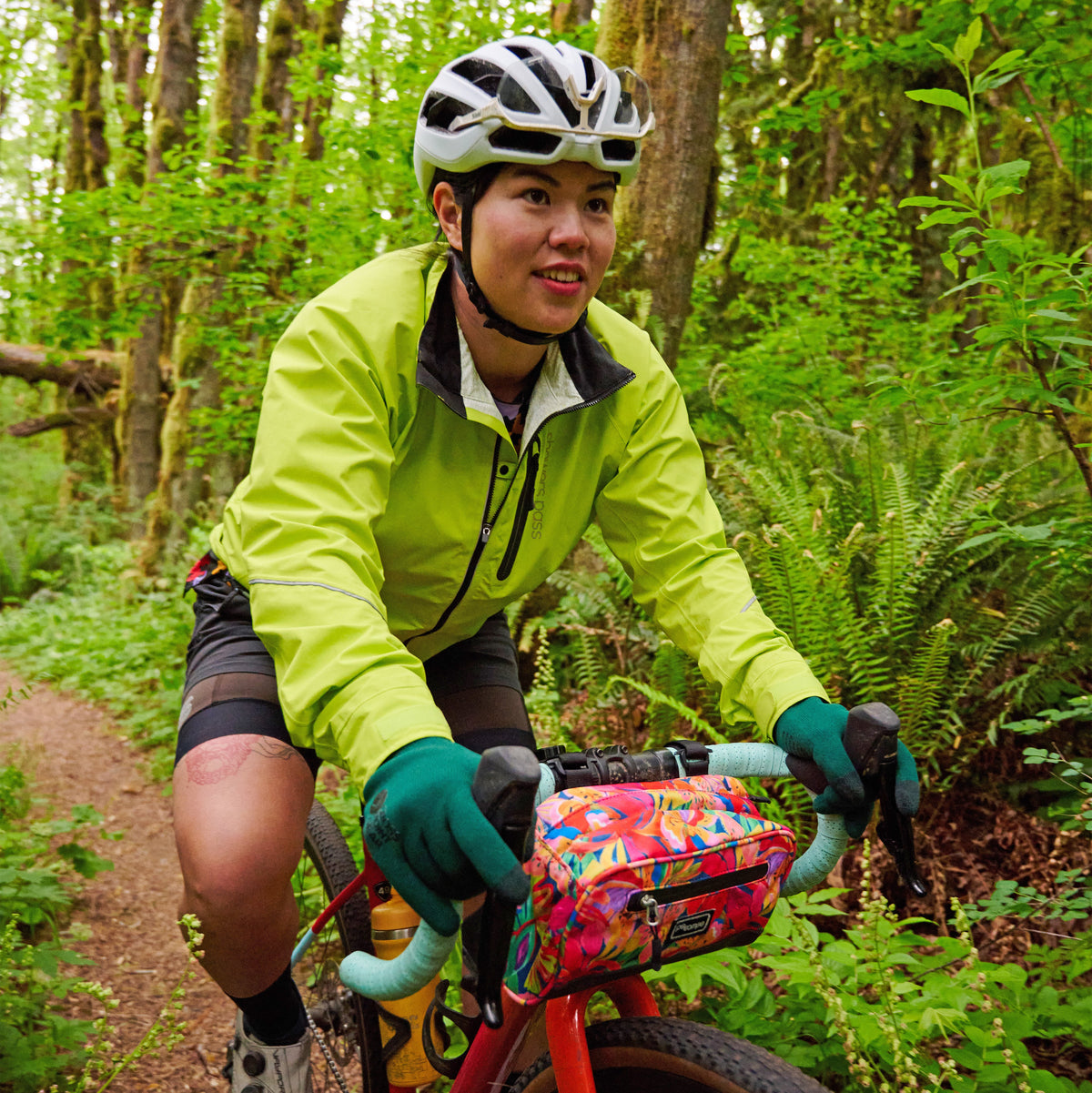 Women's Century Jacket, hi-vis yellow, worn by a rider on a forest trail