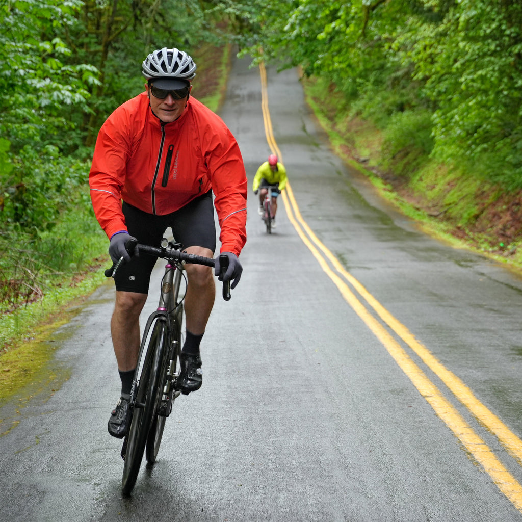 Men's Century Jacket, orange, worn by a rider on a wet road