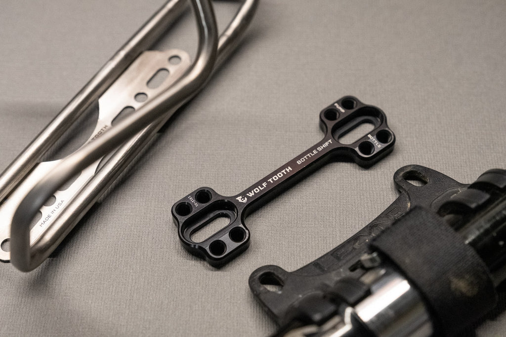 Wolf Tooth B-RAD Bottle Shift, two mounts with a bottle cage on a workbench