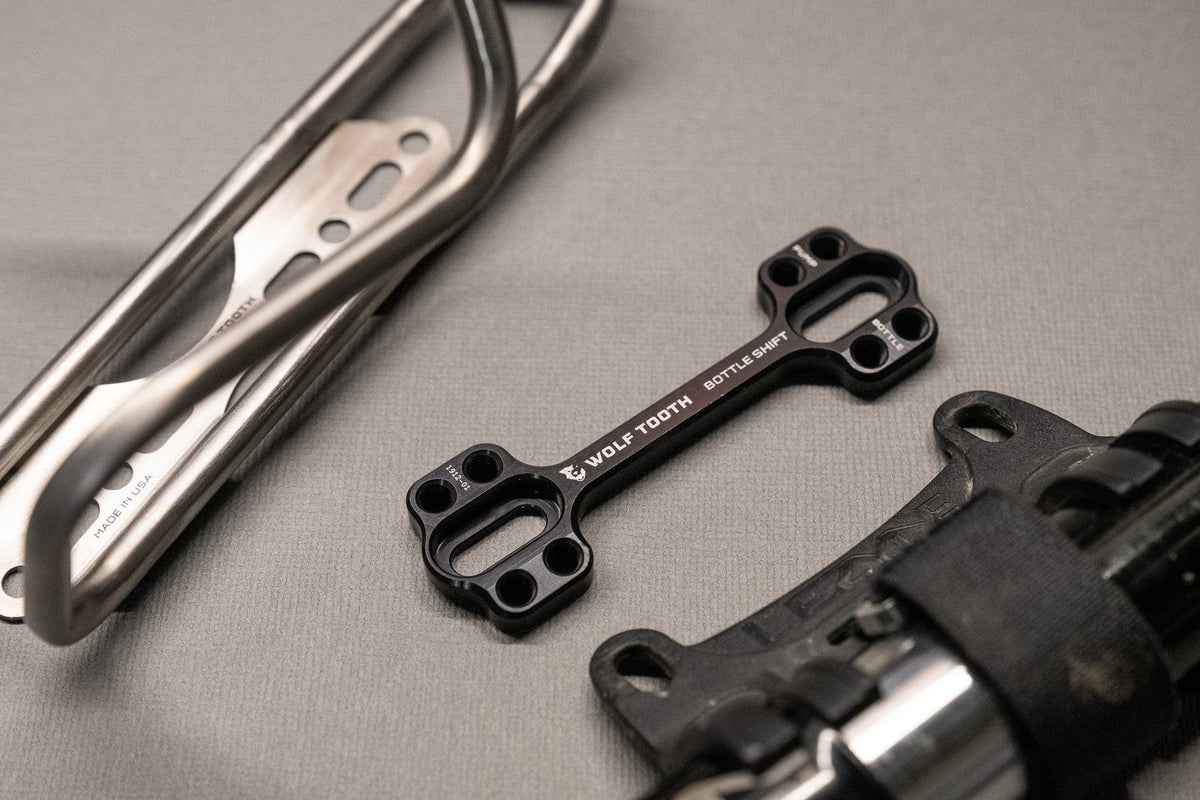 Wolf Tooth B-RAD Bottle Shift, two mounts with a bottle cage on a workbench