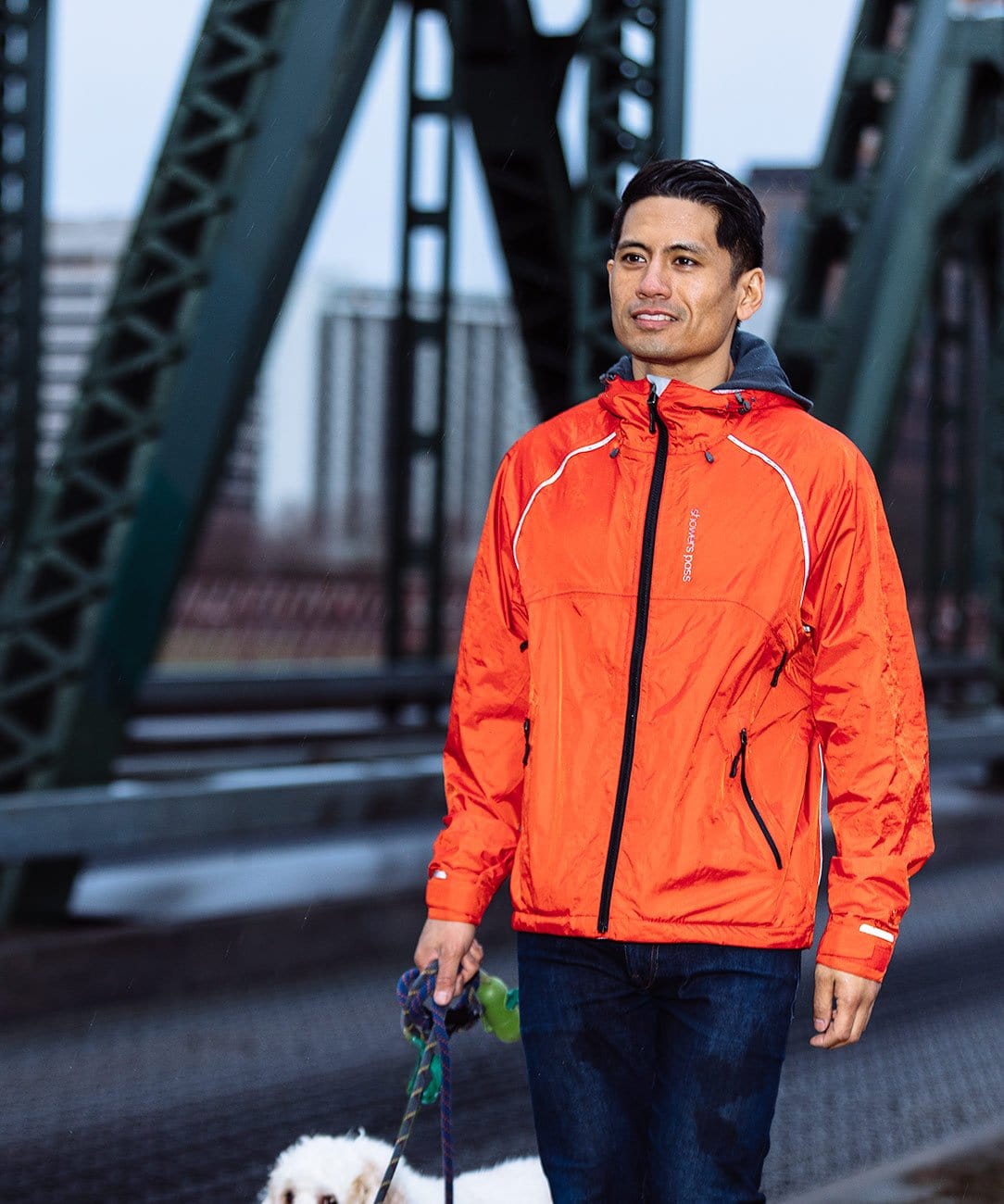Men's Syncline CC Jacket, orange, worn while walking a dog on a bridge