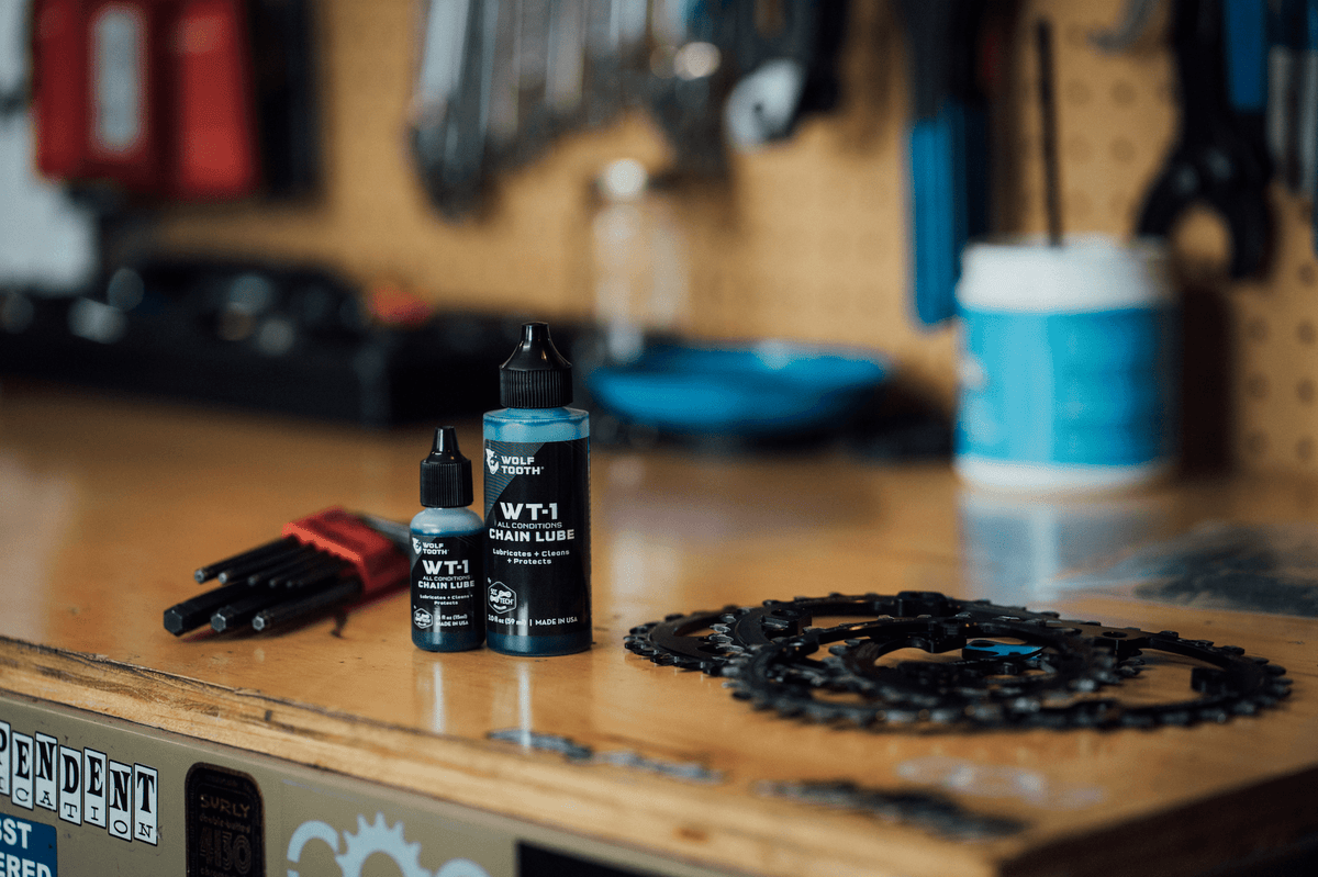 Wolf Tooth WT-1 Chain Lube, two bottle sizes on a workshop bench
