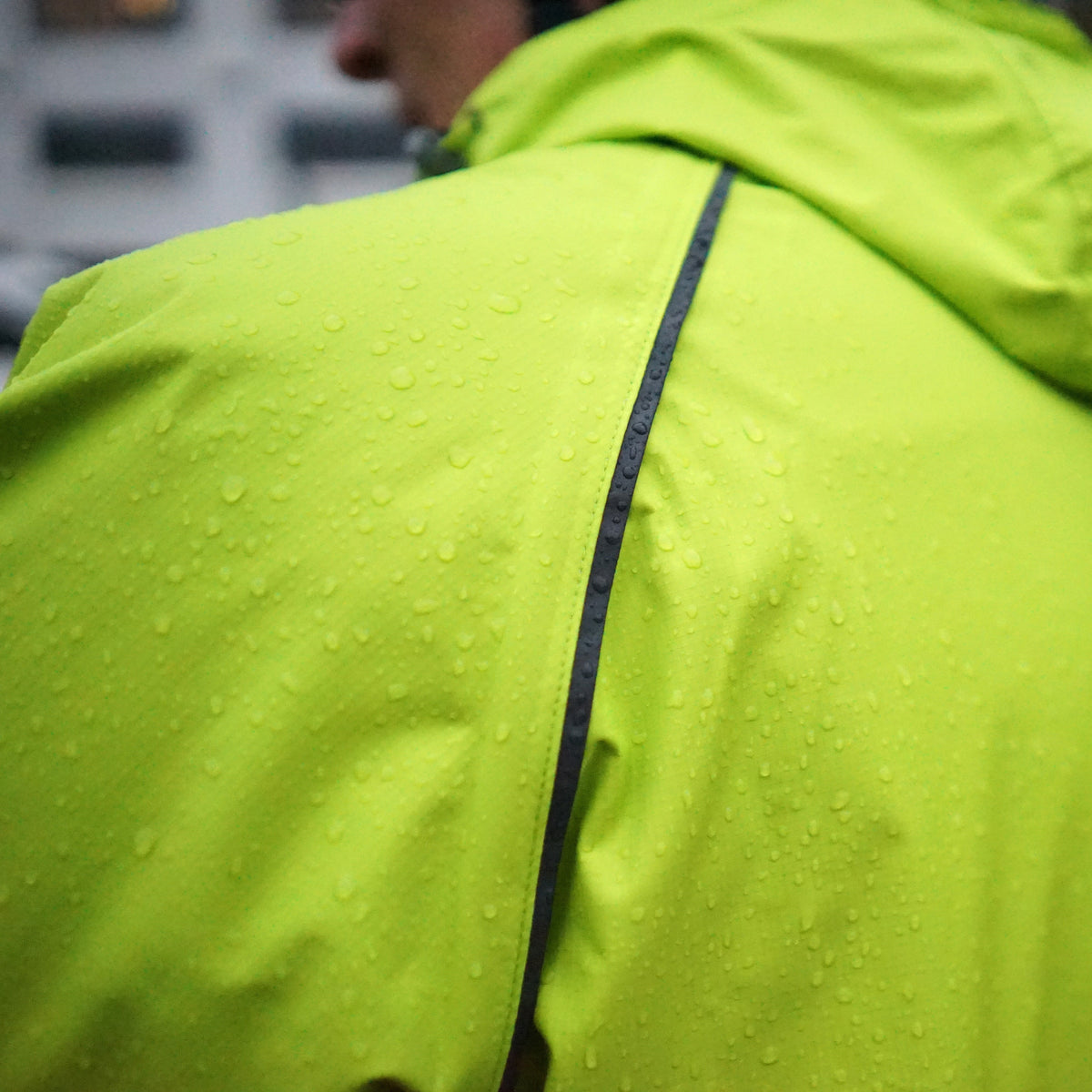 Men's Syncline CC Jacket, hi-vis yellow, close-up of the back vent in the rain