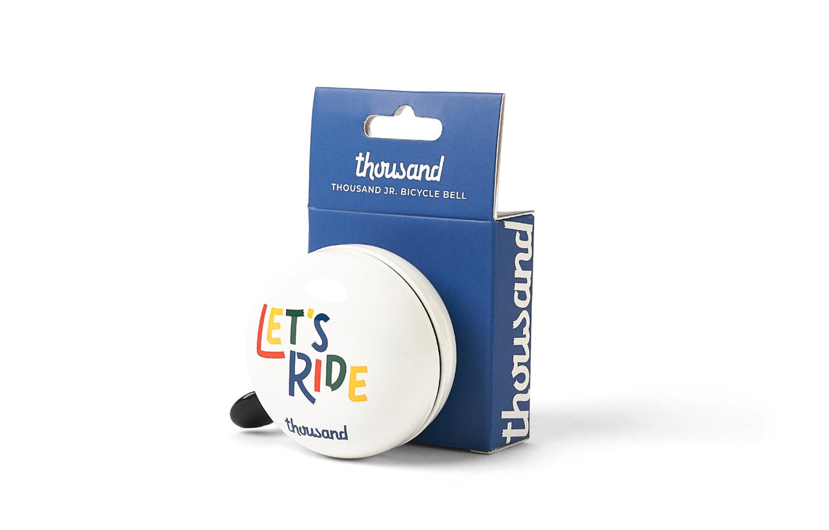 Thousand Jr. Bicycle Bell, white with "Let's Ride" print, in packaging
