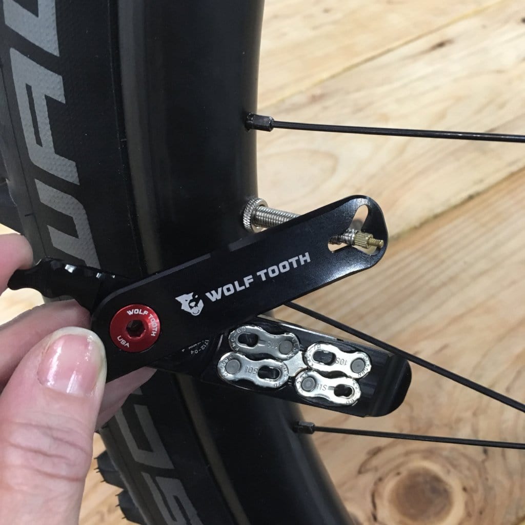 Wolf Tooth Pack Pliers, open next to a wheel with stored master links