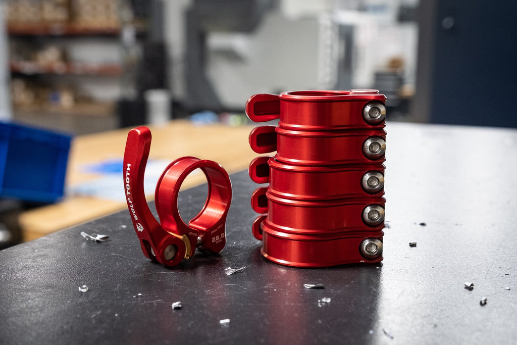 Wolf Tooth Seatpost Clamp, Quick Release, red clamps stacked on a workbench