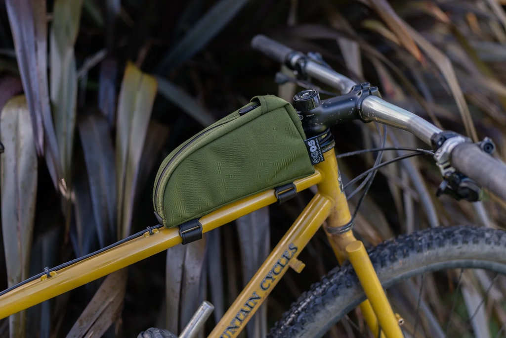 Outer Shell top tube bag in olive, strapped to the top tube of a yellow bike