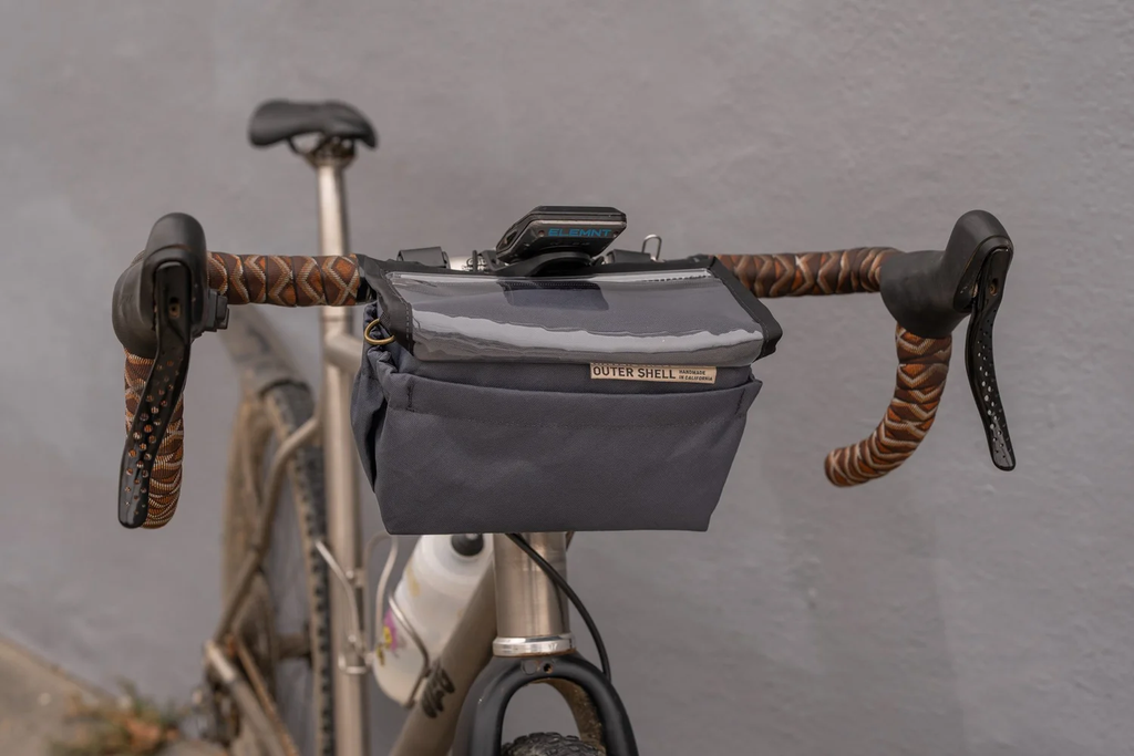 Outer Shell drawcord handlebar bag in grey, mounted on the drop bars of a tan touring bike