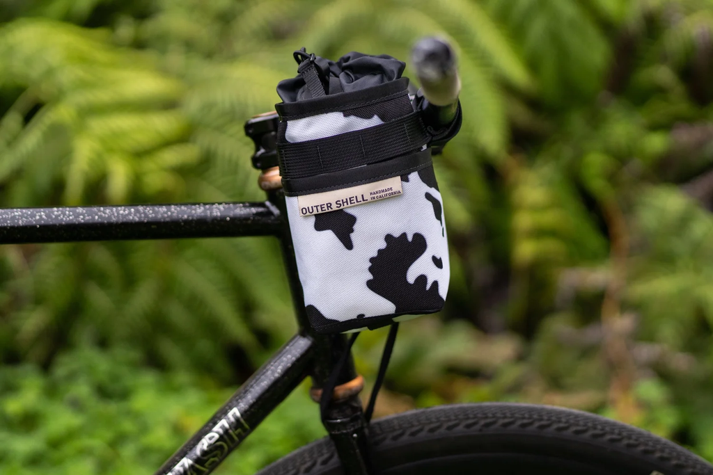 Outer Shell stem caddy in cow print, mounted beside the stem on a mountain bike
